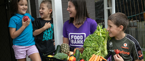 food bank employee with kids and fruit and vegetables